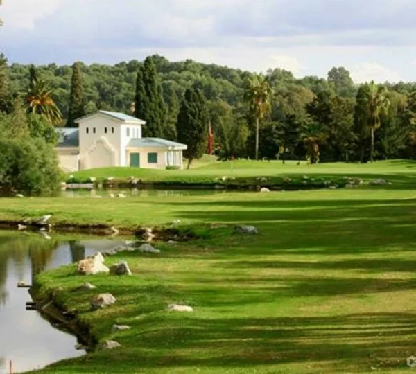 Vista panorámica del Royal Country Club de Tánger, mostrando el campo verde, los árboles centenarios y las vistas al Estrecho de Gibraltar en el horizonte. Así es el Golf de Lujo en Tánger